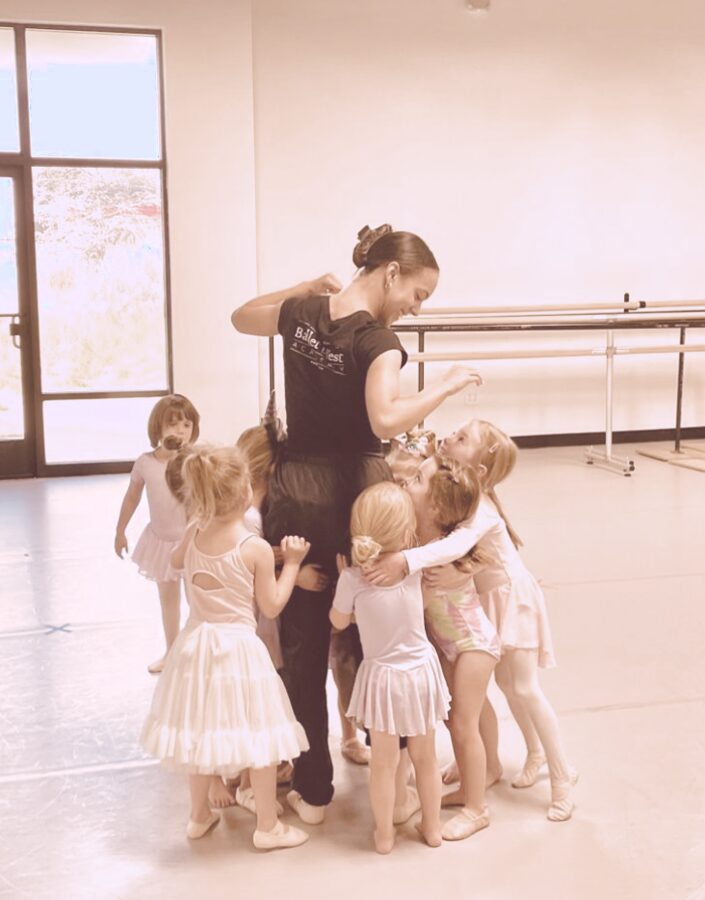 Instructor surrounded by students for a group hug after class