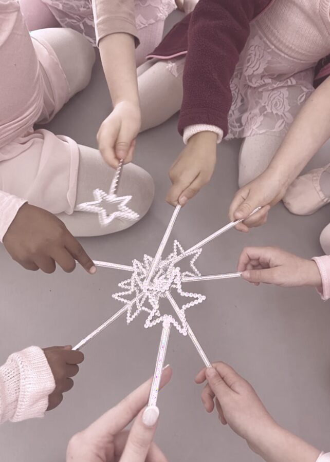 Dancers holding sparkly star wands together in a circle