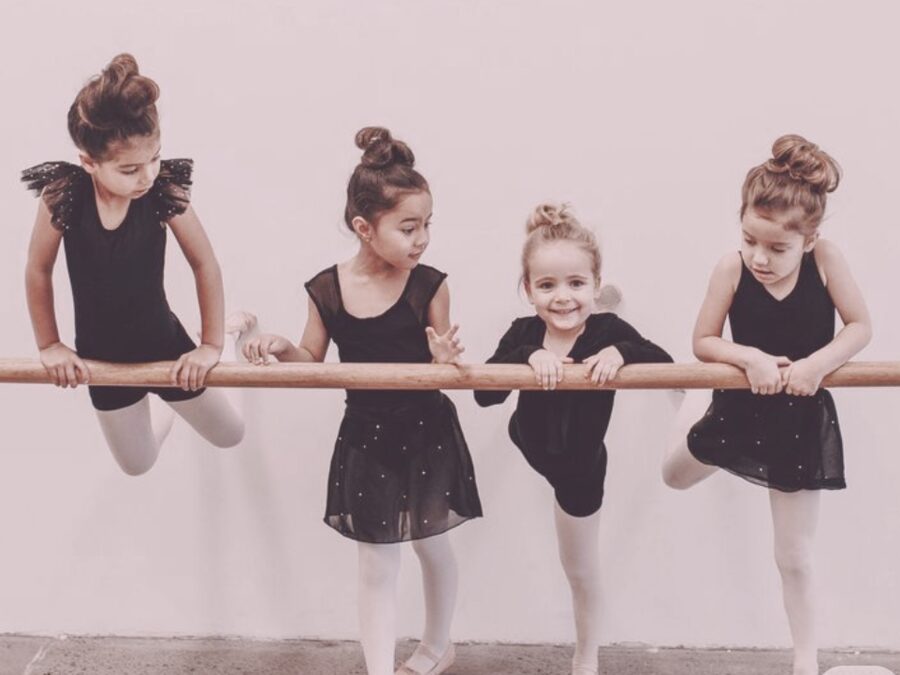 Little dancers stretching at the ballet barre in class