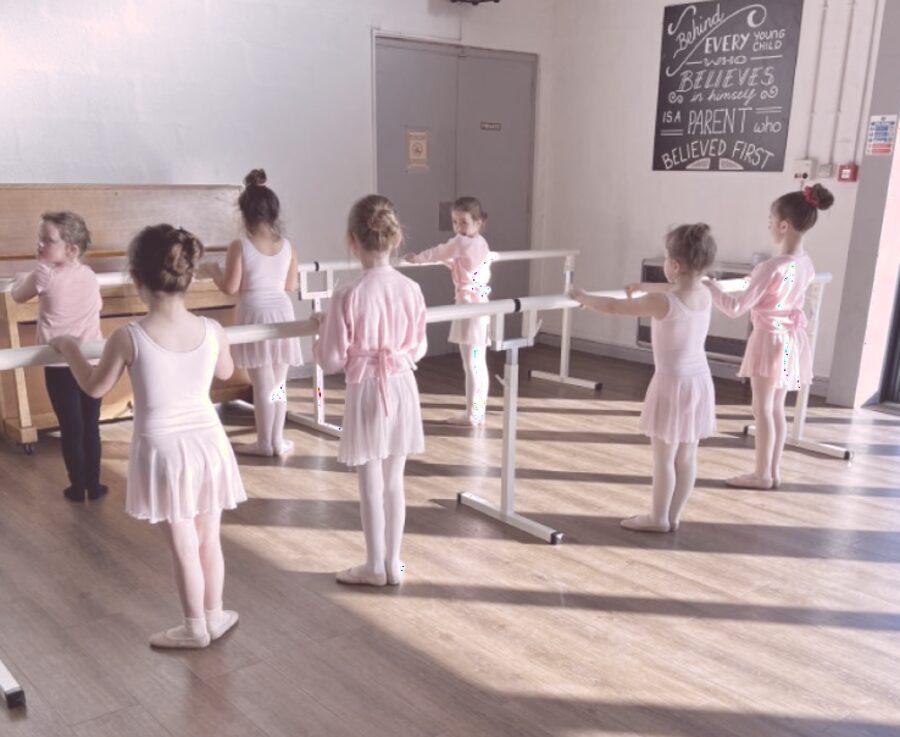 Dancers practicing at the barre beneath an inspiring quote